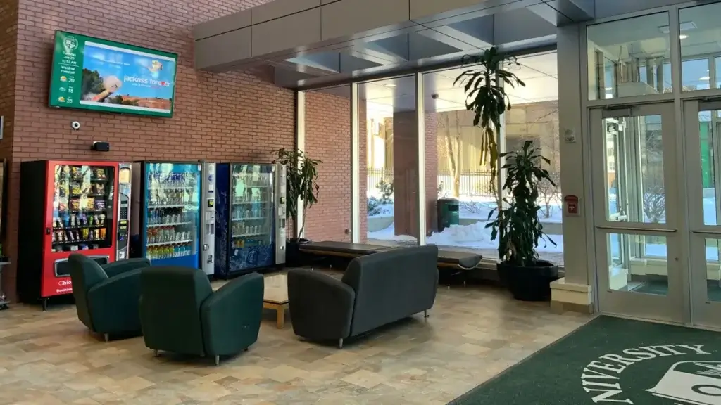 University lounge digital signage by Reach Media Network featured above snack and drink machines.