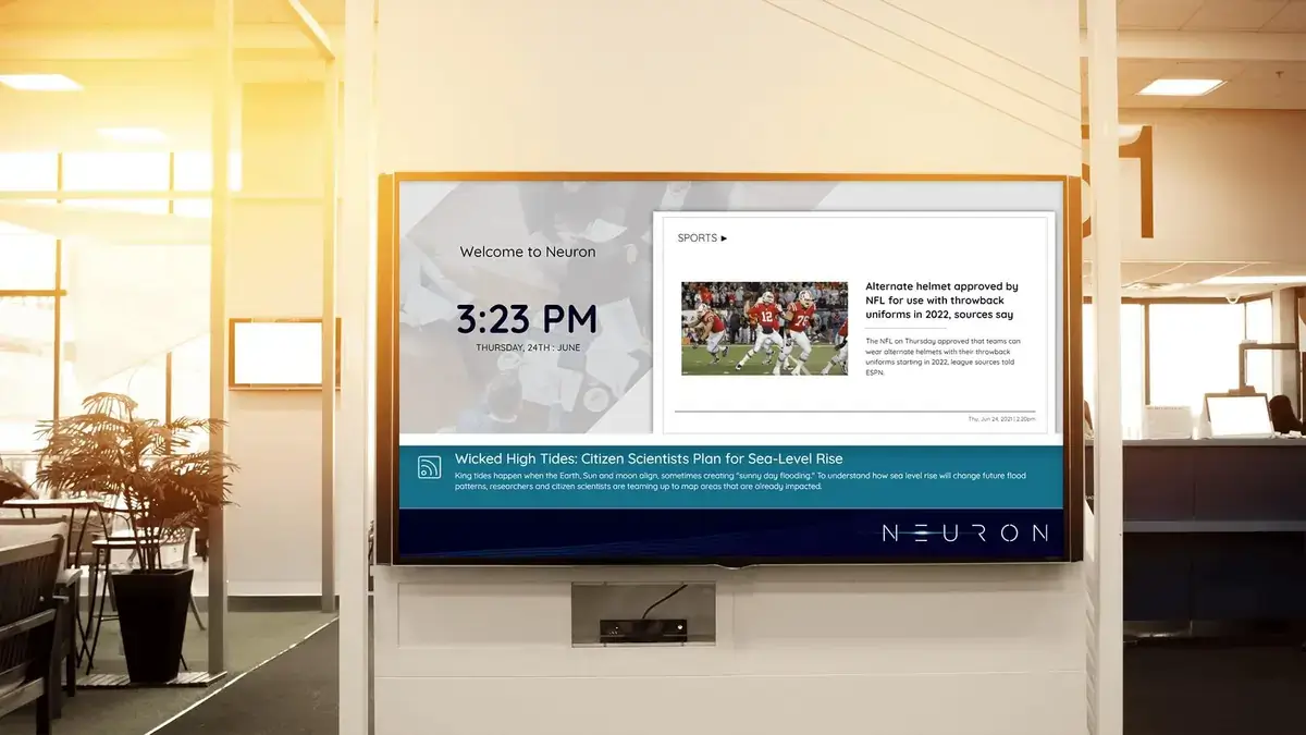 Neuron digital signage screen from Reach Media Network featured in office environment and displaying welcome message, sports headlines.