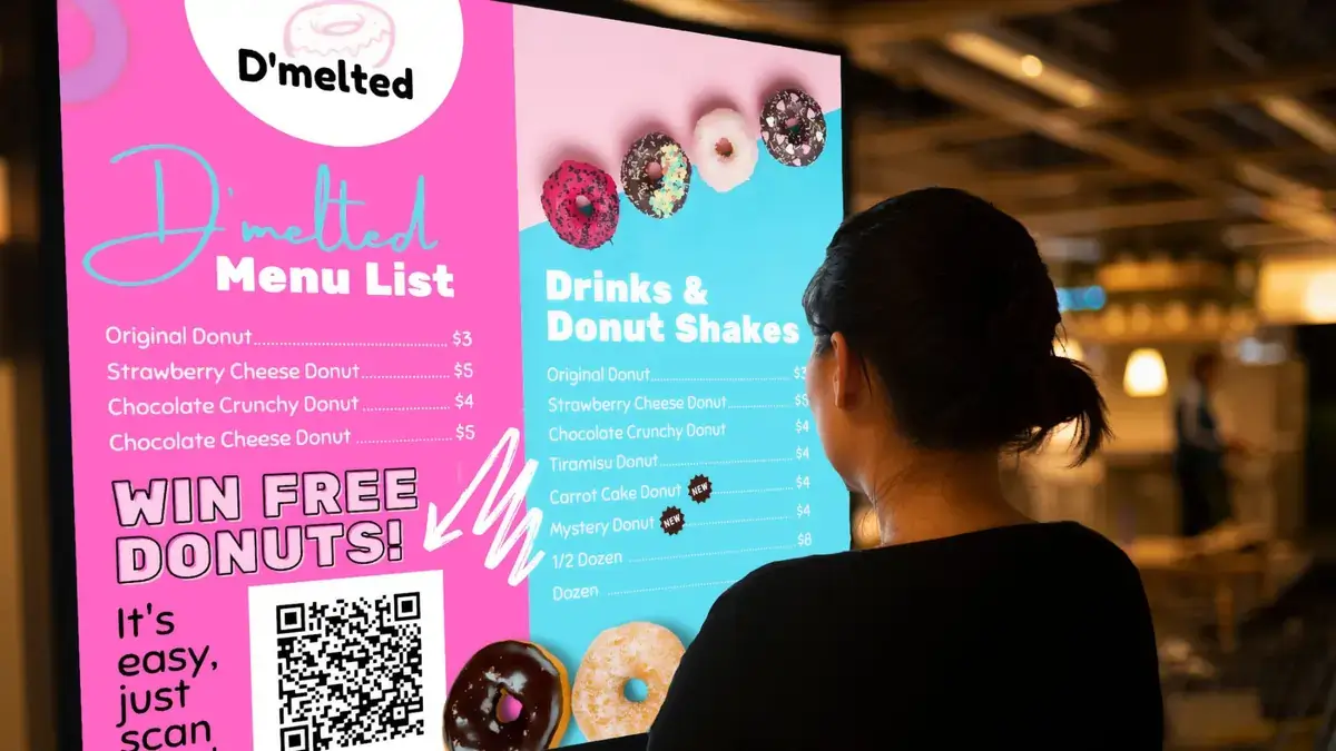 Customer looking at the D'melted digital signage menu board from Reach Media Network